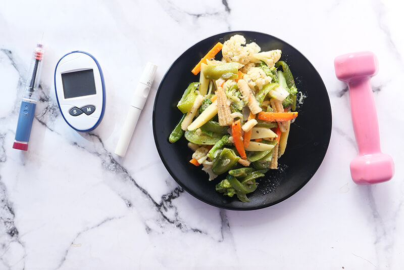 Insulin pens and a selection of healthy foods on a table for diabetes management.