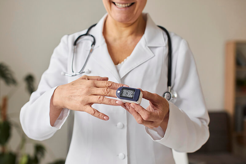 Elderly woman smiling while using a pulse oximeter in a recovery center