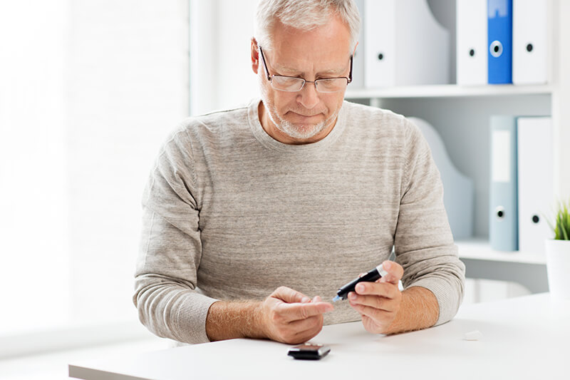 Elderly man checking blood sugar levels